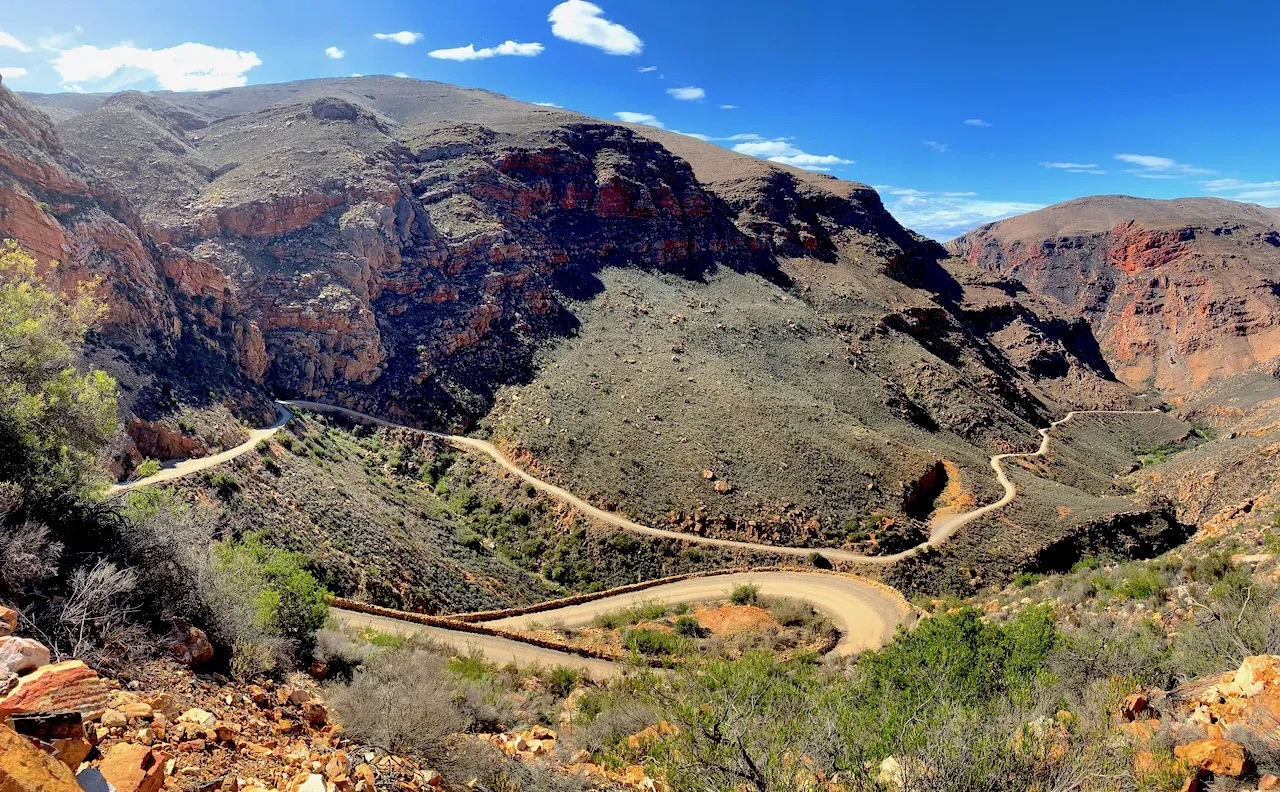 Hårnålssvinger på et gravelpass skåret inn i rød stein i Western Cape