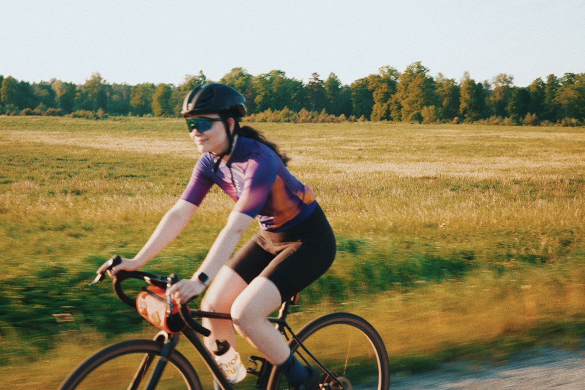Rytter i cykeltøj og hjelm på en gruslandevej i aftenlys